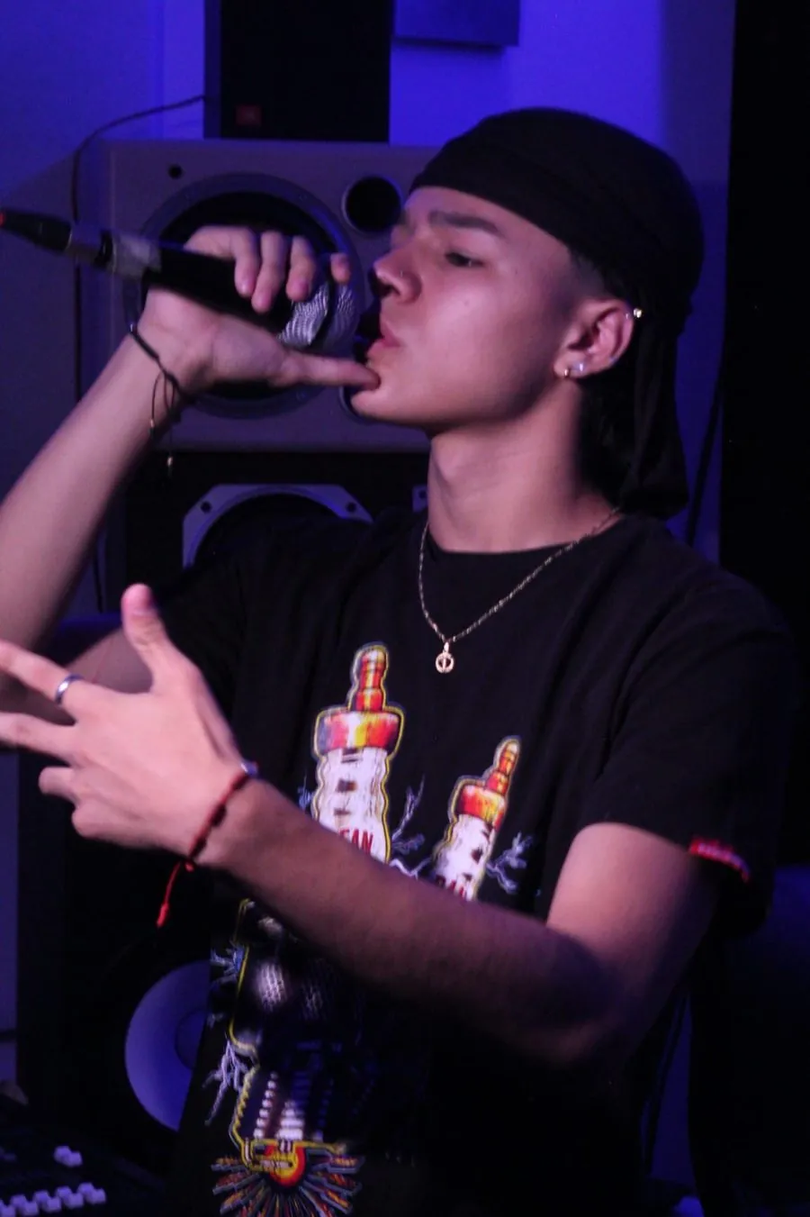 Mainyy cantando al micrófono en el estudio